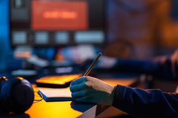 cybercrime, hacking and technology concept - close up of male hacker in dark room writing to...