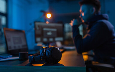 cybercrime, hacking and technology concept - close up of male hacker in dark room with headphones...