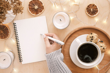 Back to life, goal list concept. Woman's hand writing in empty notebook on wooden table....