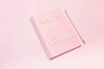 Inscription back to school on a pink notepad with school supplies