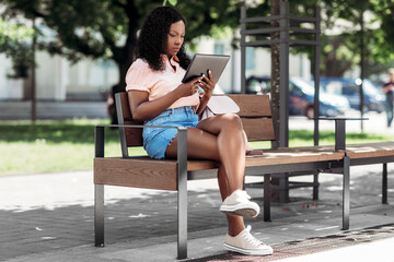 technology, lifestyle and people concept - african american woman with tablet pc computer in city