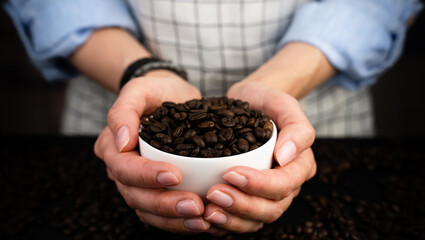 Woman's hands hold a cup of aromatic coffee beans. The process of making natural coffee. Arabica. Close-up. Selective focus. - obrazy, fototapety, plakaty
