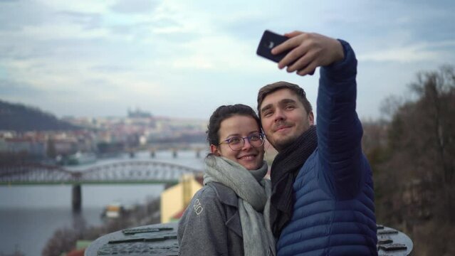 Romantic couple taking selfie photo and kiss in front of Prague lookout, Upper Castle, front middle shot