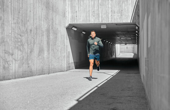 fitness, sport and healthy lifestyle concept - young man running out of tunnel - Powered by Adobe