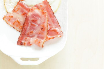 Pan fried bacon on white plate for homemade breakfast 
