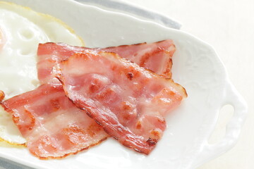 Pan fried bacon on white plate for homemade breakfast 