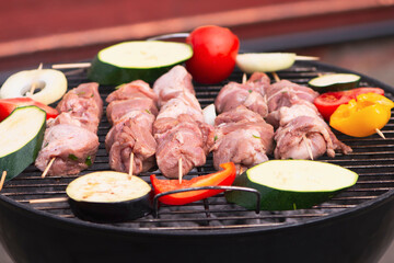 raw pork neck meat is cooked on the grill with vegetables in nature in summer