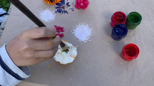 Close-up of children's hands that create a drawing using a flower by poking. What to do with children in kindergarten or school camp in the summer.