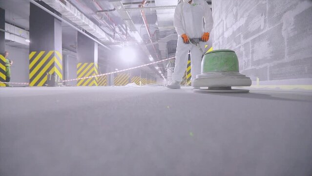Processing a concrete floor with a grinder close-up. Grinding concrete floor grinding machine large floor. Builder works concrete floor with special equipment