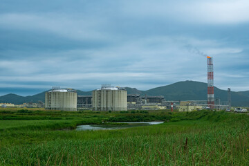 Fototapeta na wymiar plant for the production of liquefied natural gas in a natural area against the backdrop of mountains
