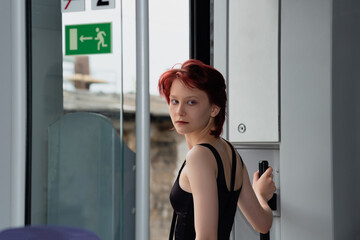 young woman is preparing to get off at a stop from a suburban train car