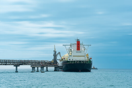 liquefied natural gas carrier tanker during loading at an LNG offshore terminal, in the distance the oil export terminal is visible in the sea