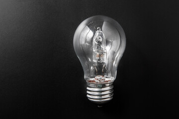 electricity, energy and power consumption concept - close up of lightbulb on black background - obrazy, fototapety, plakaty