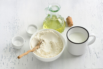 Ingredients for baking buns: wheat flour, yogurt, vegetable oil, salt, baking powder on a light blue background, top view. Cooking delicious homemade food