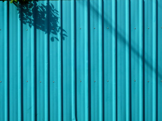 blue metal sheet of fence with shadow of sunlight