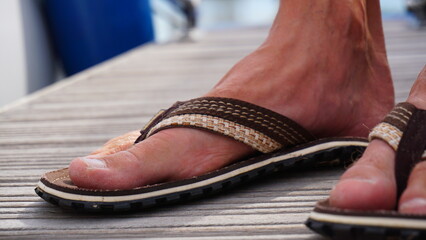 Flip flop with man foot. Summer shoes with bare feet. Flip flops for warm days and holiday walks in the great outdoors.