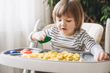 Cute little boy playing with kinetic sand. Development of fine motor skills. Early sensory...
