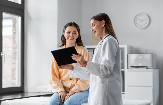 medicine, healthcare and people concept - female doctor with tablet pc computer talking to smiling woman patient at hospital