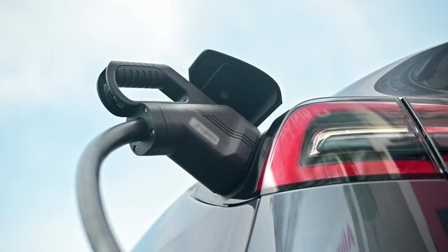Close view of a charger plugged into an electric car at a charging station