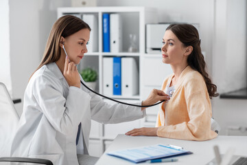 medicine, healthcare and people concept - female doctor with stethoscope and woman patient at...