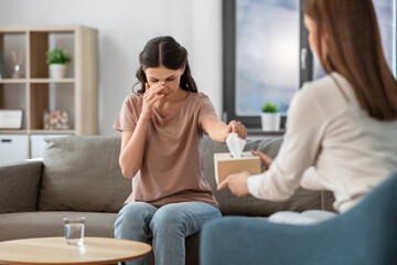 psychology, mental health and people concept - crying woman patient taking paper tissue from psychologist at psychotherapy session