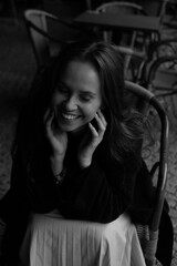 Sensual portrait of a young brunette in a white dress. Girl in a autumn wear is sitting in a chair 