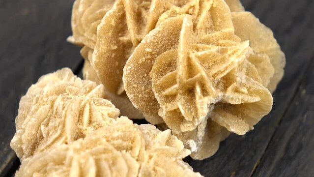 Sample of a desert rose rock mineral stone rotates on a dark wooden background 