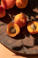 Organic ripe apricots under sun shadows on the brown wooden board close up