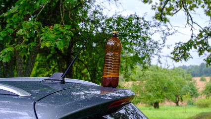 A brown plastic beer bottle on the roof of a car
