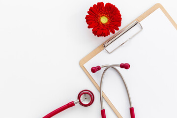 Women health. Doctor gynecologist clipboard with red flower and stethoscope