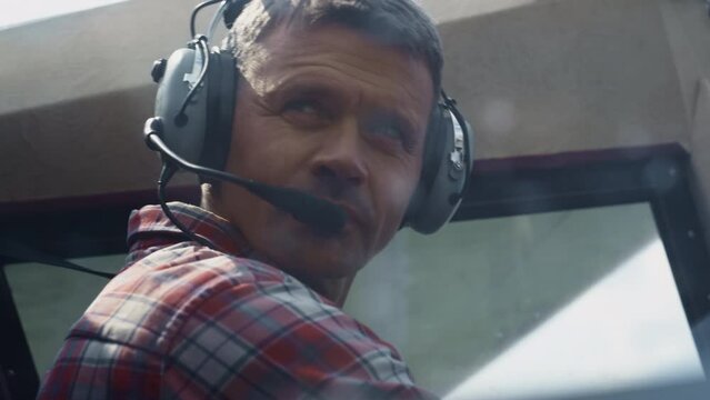 Closeup airplane pilot face wearing headset with microphone sitting plane cabin.