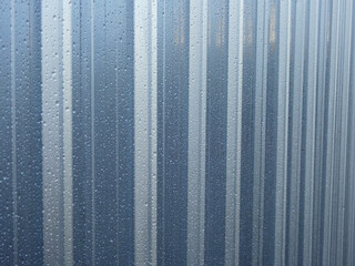 raindrops on silver metal sheet of fence after rain
