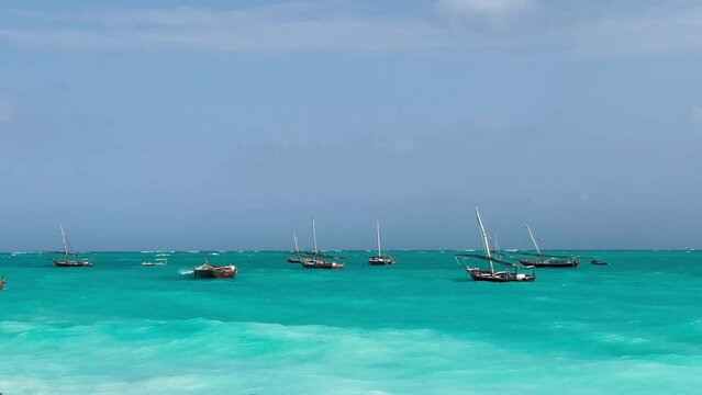 4K wooden fishing and touristic boats rocking on blue-emerald waves of ocean. Nature, ocean, environment concept.