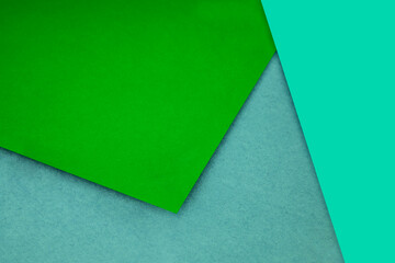 Plain and Textured neon blue green papers randomly laying to form M like pattern and triangle for creative cover design idea