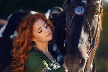 Medieval woman princess in green dress sits astride black steed horse.