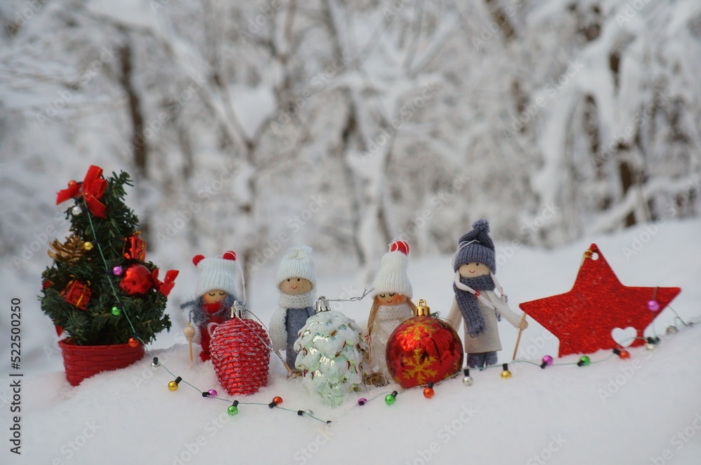 Poster Toy angels on skis, decorated with a scarf and a hat. Figurines in the winter forest.  Christmas decorations and decorations. Christmas tree with toys.