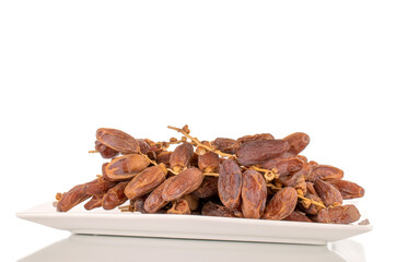 Several branches with dry sweet dates on a ceramic plate, close-up, isolated on a white background.