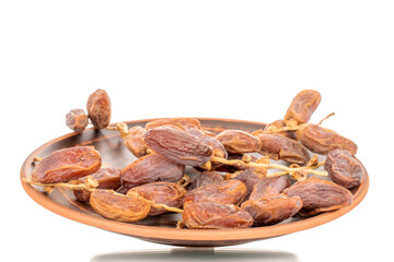 Several branches with dry sweet dates on a ceramic plate, close-up, isolated on a white background.