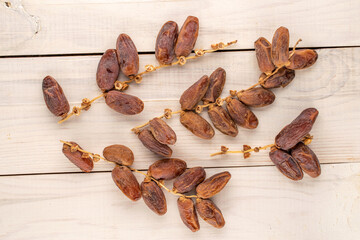 Several branches with dry sweet dates on a wooden table, close-up, top view.