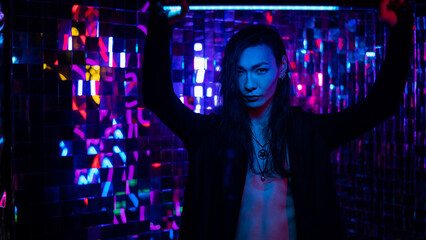 Portrait of a transgender model with a naked torso in a studio with neon lighting.