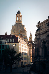 Obraz premium The dome of Frauenkirche peeking up behind other buildings in the evening sunlight in Dresden Germany