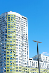 Fototapeta premium Multi-storey building in the form of a cylinder and painted in white and green colors against a blue sky.