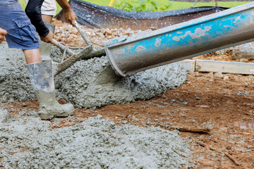 Pouring wet concrete while paving a driveway at construction site near new home
