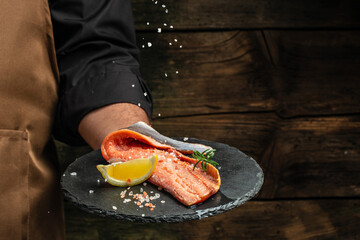 chef prepares salmon steak, process of sprinkling with spices and salt in a freeze motion,...