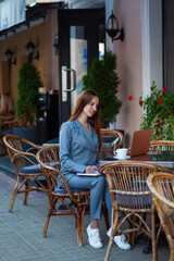 Beautiful confident woman. Woman on the street at the table . Business consultant, to note down, to make notes. Business meeting. Woman with notebook. Business look.