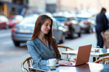 Beautiful professional ht manager woman in a fashion business suit working on a laptop and drinking coffee