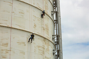 Male two worker inspection wearing safety first harness rope safety line working at a high place on tank roof spherical