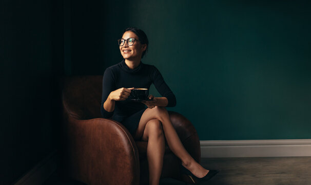 Businesswoman sitting on armchair with cup of tea