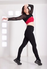 A beautiful slim brunette posing in a white futuristic studio