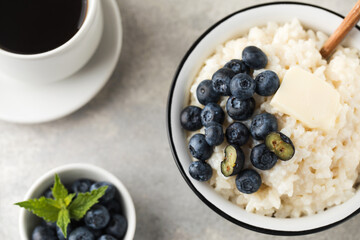 Rice milk porridge with blueberries and a mug of black coffee close-up. Healthy breakfast.